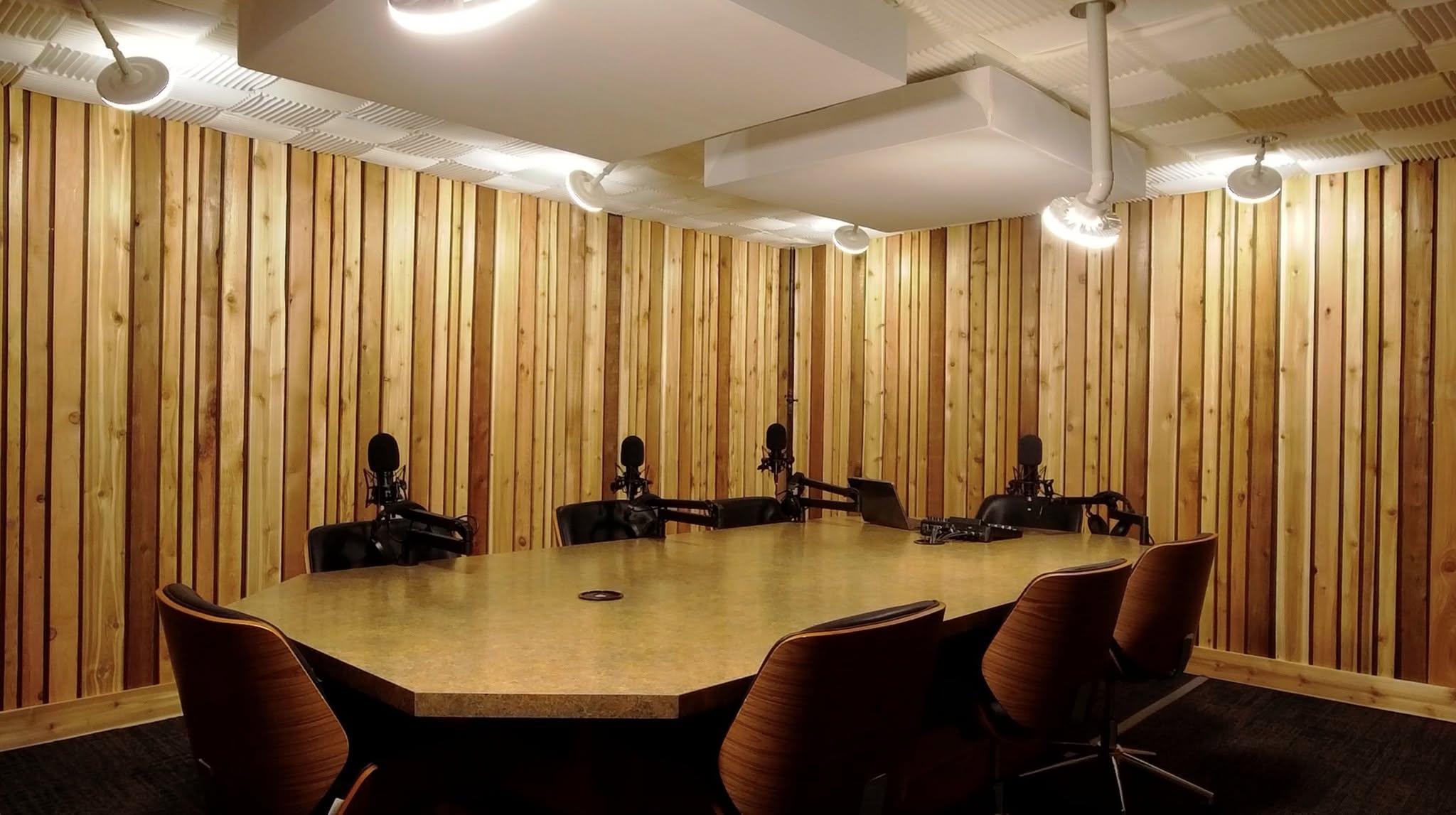 Cedarwood Studios — cedar-panelled podcast recording studio with a multi-mic table